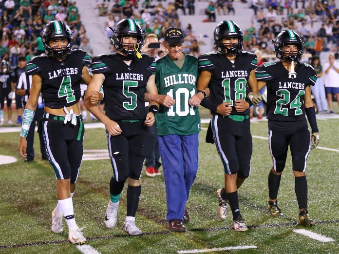 Former Hilltop High School teacher and World War II veteran Tom Rice (101) accompanies current Lancers Marko Aki (4), Gage Scruggs (5), Javin Deanda (18) and Tony Candelaria (24) during last Friday’s pre-game recognition ceremony. Photo by Jon Bigornia (Star News)